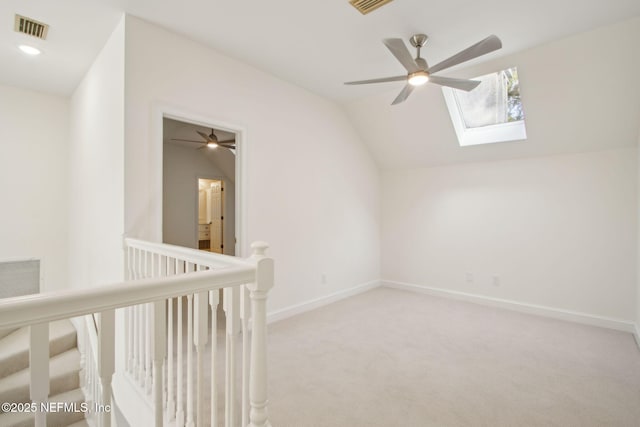 additional living space featuring carpet floors, visible vents, lofted ceiling with skylight, and ceiling fan