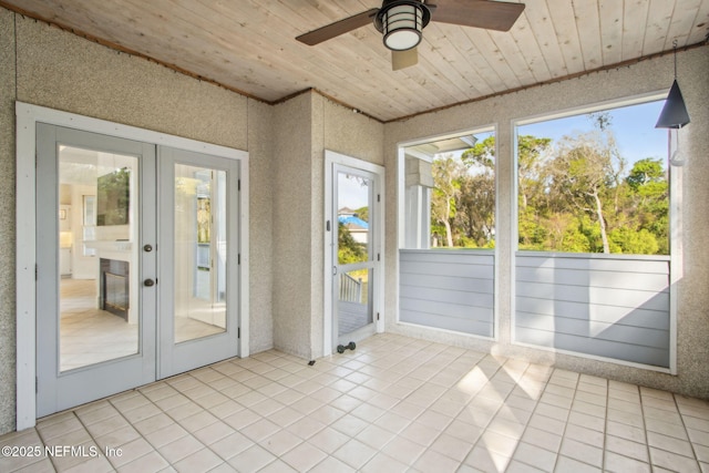 unfurnished sunroom featuring ceiling fan and french doors