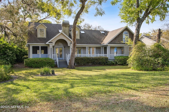 cape cod house with roof with shingles, a chimney, covered porch, a front yard, and stucco siding