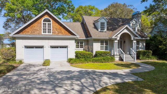 view of front of house with a chimney, concrete driveway, stucco siding, a front yard, and a garage