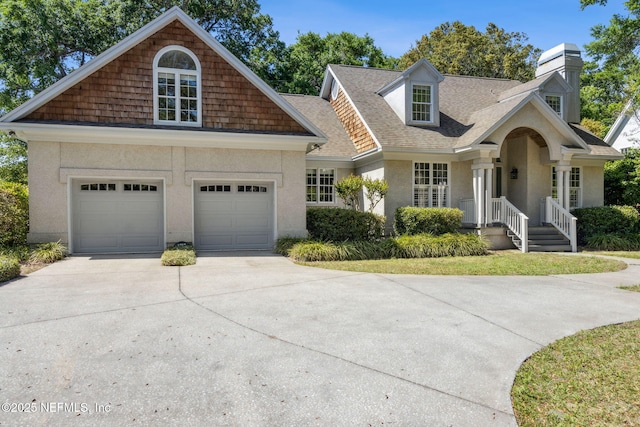 view of front of property featuring a garage, driveway, a chimney, and stucco siding