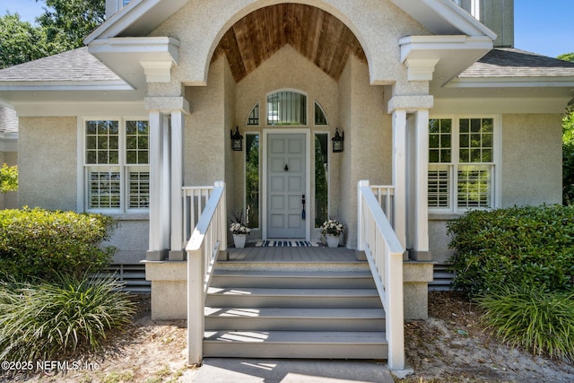 property entrance featuring roof with shingles and stucco siding