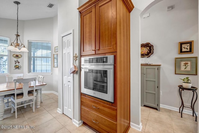 714 Copperhead Cir, Saint Augustine, FL 32092 - kitchen with visible vents, brown cabinets, stainless steel oven, pendant lighting, and light tile patterned floors