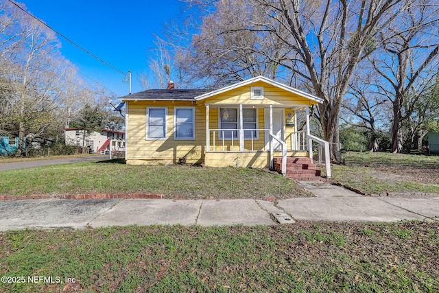 1533 W 16th St, Jacksonville, FL 32209 - bungalow with covered porch, a chimney, and a front yard