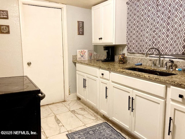 1533 W 16th St, Jacksonville, FL 32209 - kitchen with marble finish floor, black range with electric cooktop, white cabinetry, a sink, and light stone counters