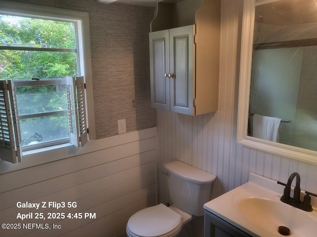 bathroom featuring toilet, a wainscoted wall, wood walls, and vanity