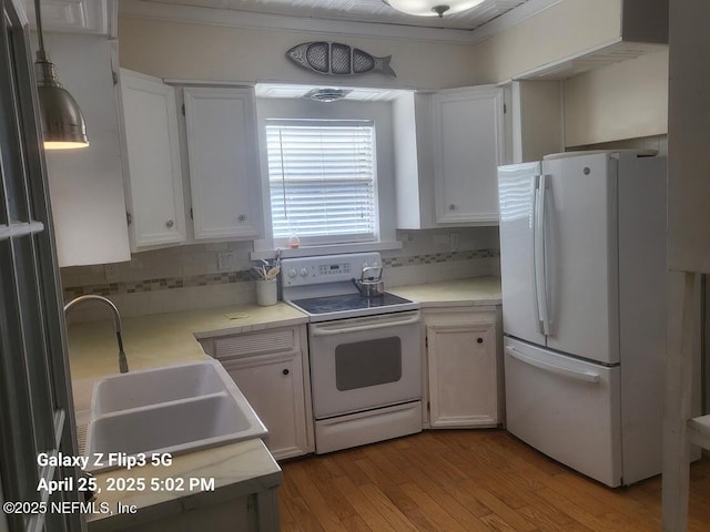 kitchen featuring a sink, wood finished floors, decorative backsplash, and white appliances