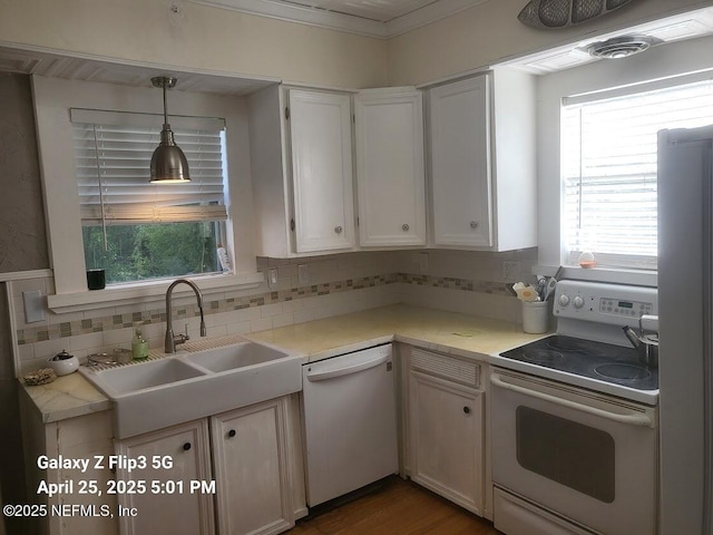 kitchen featuring a sink, white appliances, light countertops, and decorative backsplash
