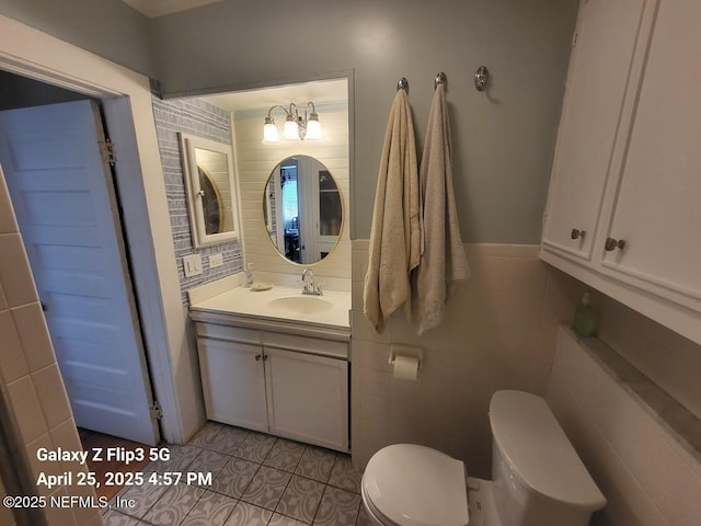 bathroom with toilet, tile patterned floors, tile walls, and vanity