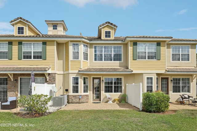535 Hedgewood Dr, Saint Augustine, FL 32092 - rear view of house with stone siding, central air condition unit, fence, and a patio area