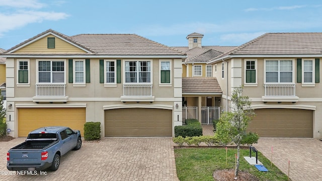 535 Hedgewood Dr, Saint Augustine, FL 32092 - townhome / multi-family property with decorative driveway, a chimney, an attached garage, a tile roof, and stucco siding