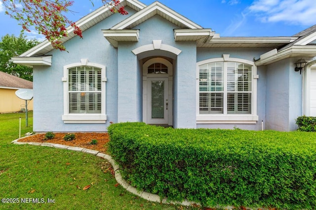 property entrance with a yard and stucco siding