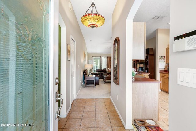 foyer entrance with light tile patterned floors, baseboards, arched walkways, and visible vents