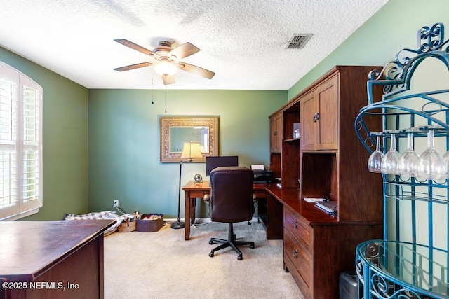 office area featuring visible vents, baseboards, ceiling fan, a textured ceiling, and light carpet