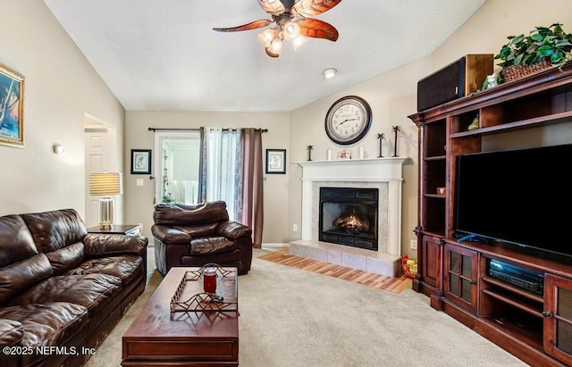 living room featuring a textured ceiling, a ceiling fan, vaulted ceiling, carpet floors, and a tile fireplace