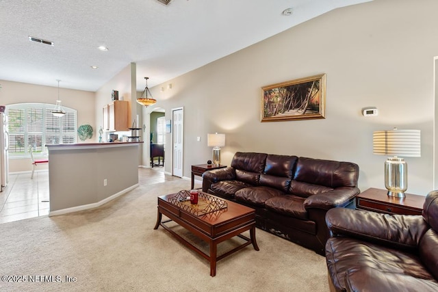 living area with visible vents, arched walkways, a textured ceiling, light colored carpet, and lofted ceiling