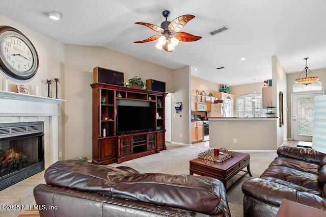 living room with light colored carpet, a ceiling fan, visible vents, a tile fireplace, and baseboards