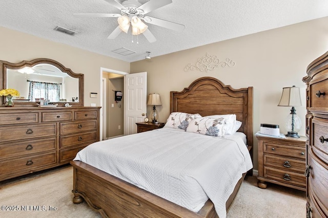 bedroom with visible vents, light colored carpet, a textured ceiling, and a ceiling fan