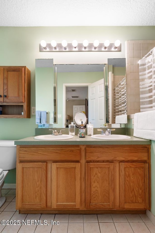 full bathroom with double vanity, a textured ceiling, a sink, and toilet