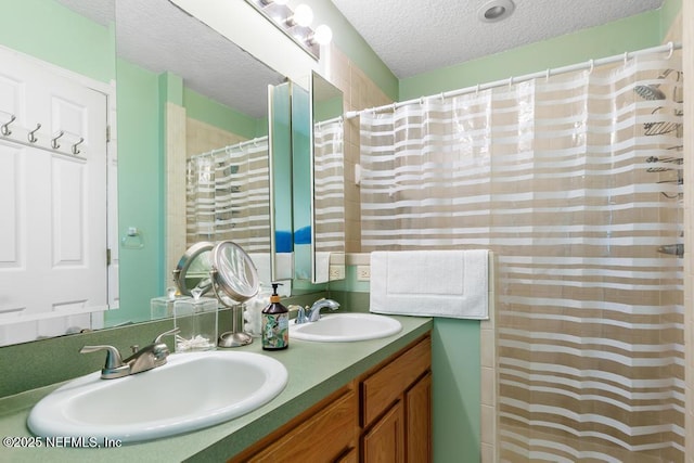 bathroom with a textured ceiling, double vanity, a sink, and curtained shower