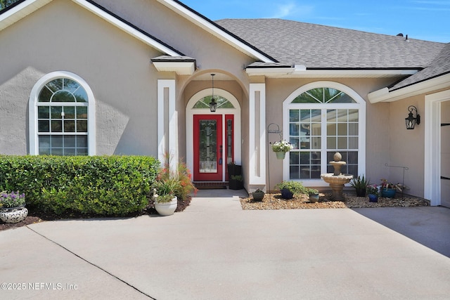 doorway to property with stucco siding and a shingled roof