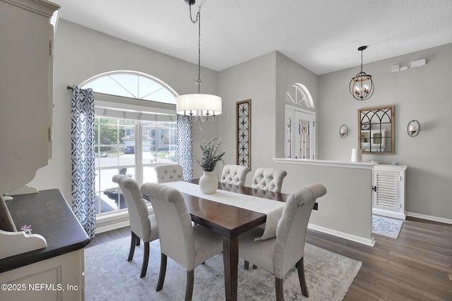 dining room with a notable chandelier, a textured ceiling, baseboards, and wood finished floors