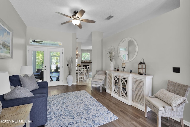 living room with french doors, wood finished floors, a textured ceiling, visible vents, and ceiling fan