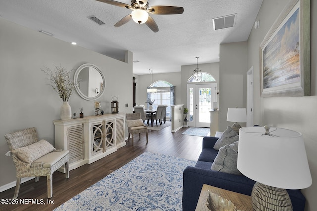 living area featuring a textured ceiling, dark wood-style floors, visible vents, and a ceiling fan