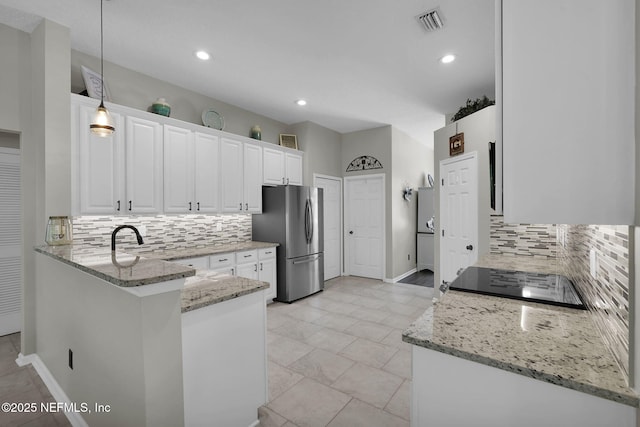 kitchen with decorative backsplash, visible vents, white cabinetry, light stone counters, and freestanding refrigerator