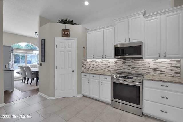 kitchen with decorative backsplash, a textured ceiling, white cabinets, light stone countertops, and appliances with stainless steel finishes
