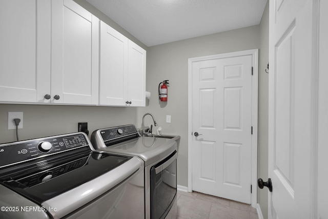 clothes washing area featuring baseboards, separate washer and dryer, cabinet space, and light tile patterned floors