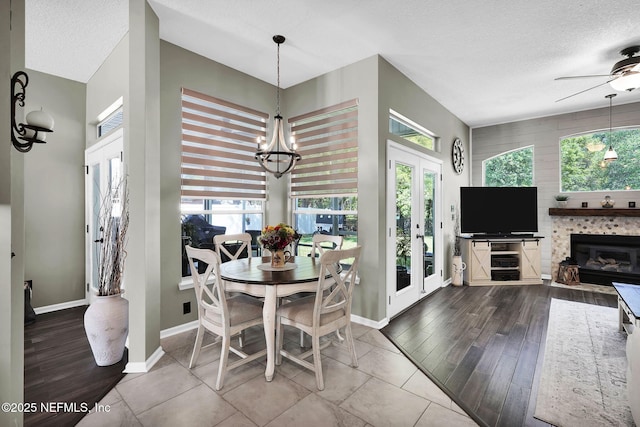 dining space with plenty of natural light, ceiling fan with notable chandelier, wood finished floors, and a textured ceiling