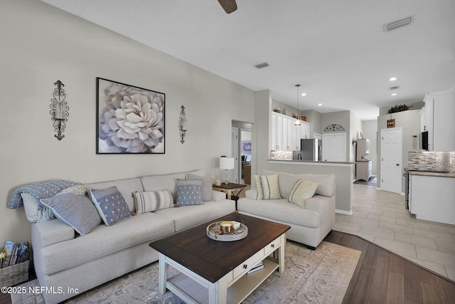 living room featuring light wood finished floors, visible vents, and recessed lighting