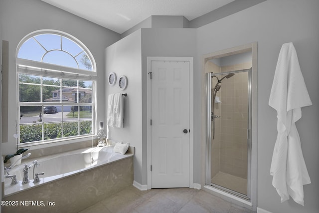 bathroom with tile patterned floors, a shower stall, a textured ceiling, a bath, and baseboards