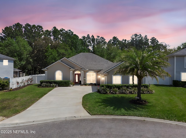 single story home featuring stucco siding, fence, concrete driveway, and a yard