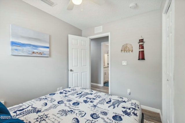 bedroom featuring a closet, wood finished floors, baseboards, visible vents, and ceiling fan