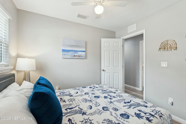 bedroom featuring baseboards, visible vents, wood finished floors, and a ceiling fan