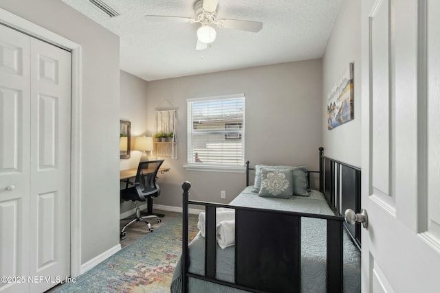 bedroom featuring a ceiling fan, wood finished floors, a textured ceiling, baseboards, and visible vents