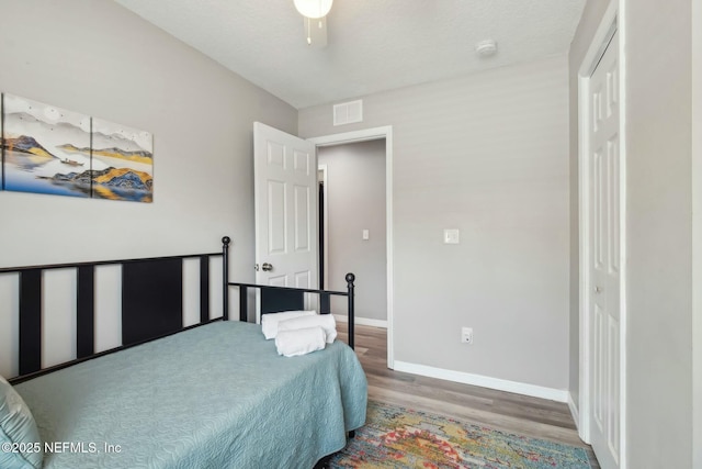 bedroom featuring wood finished floors, a closet, baseboards, and visible vents