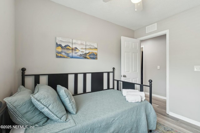 bedroom with baseboards, visible vents, wood finished floors, and ceiling fan