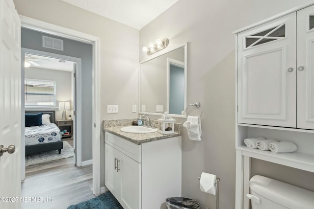 half bathroom featuring visible vents, ceiling fan, toilet, wood finished floors, and vanity