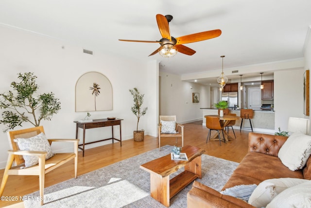 living area with ceiling fan, baseboards, light wood-style floors, and visible vents