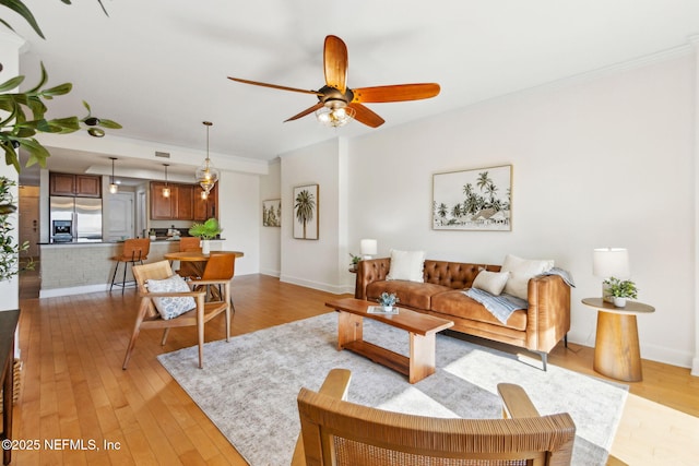 living room with ceiling fan, crown molding, and light wood-style flooring