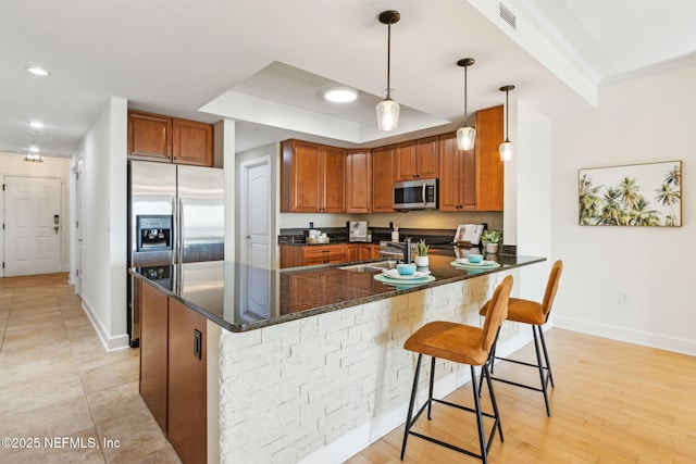 kitchen with stainless steel appliances, baseboards, a sink, and brown cabinets