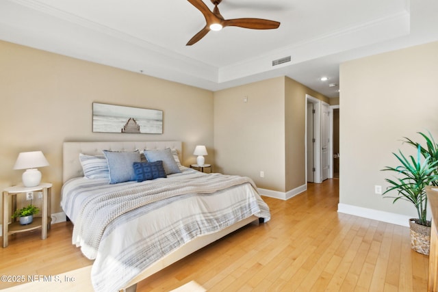 bedroom featuring visible vents, ornamental molding, baseboards, light wood-style flooring, and ceiling fan