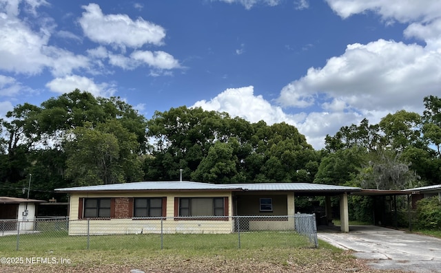 ranch-style house featuring concrete driveway, a carport, a front lawn, a fenced front yard, and metal roof