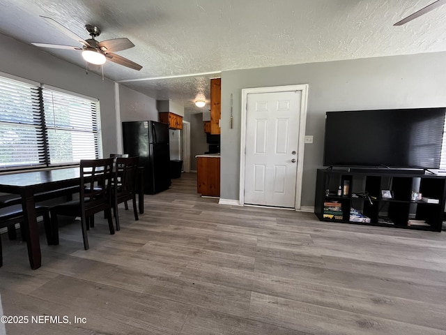 dining room featuring baseboards, a ceiling fan, wood finished floors, and a textured ceiling