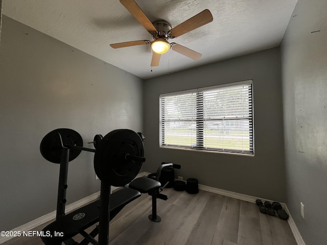 workout area featuring baseboards, ceiling fan, and wood finished floors