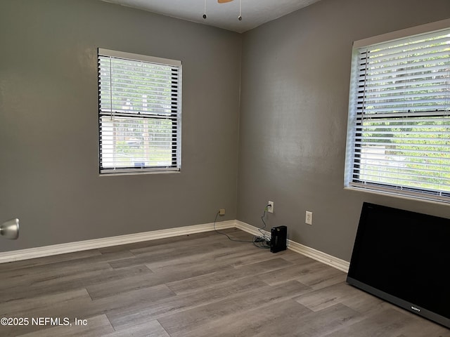 empty room featuring wood finished floors, baseboards, and plenty of natural light
