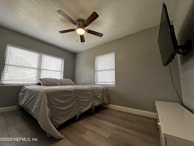 bedroom featuring a textured ceiling, baseboards, a ceiling fan, and wood finished floors